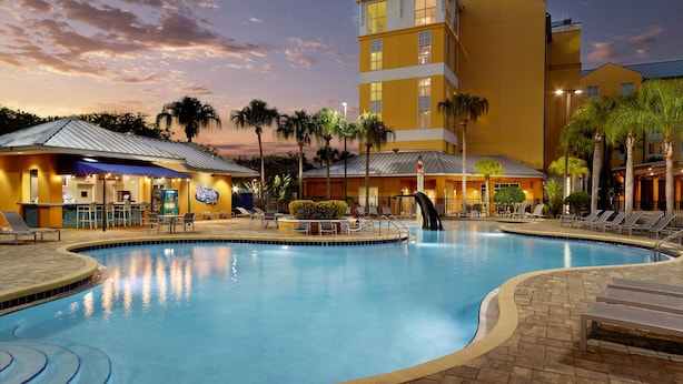 A hotel with a pool, palm trees, and a sunset sky. - Fairfield Inn & Suites by Marriott Orlando at SeaWorld (Orlando)