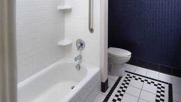 A bathroom with a white bathtub, a white toilet, and a blue shower curtain.