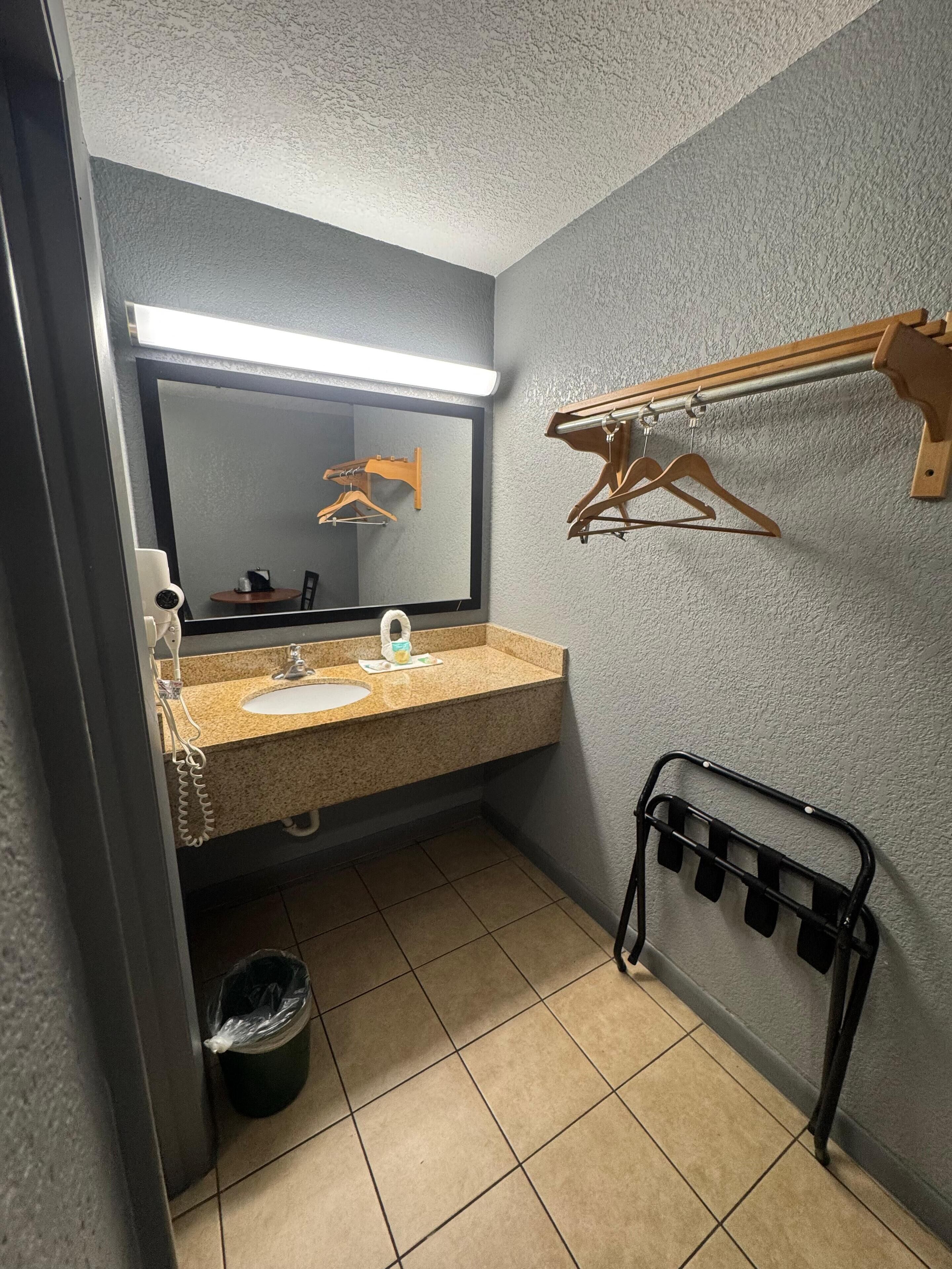 A small bathroom with a sink, mirror, and towel rack.