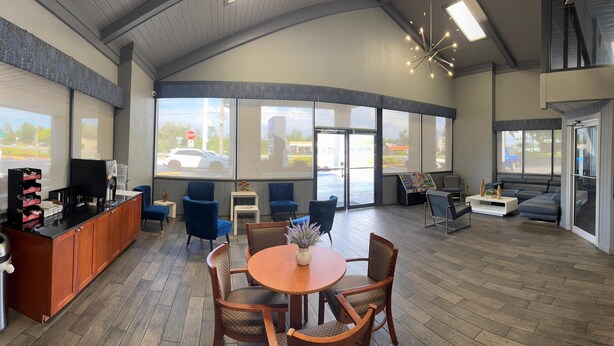 A spacious lobby with a reception desk, seating area, and large windows offering views of the street. - Budget Inn Sanford (Sanford)