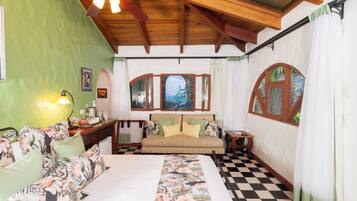 A room with a bed, a sofa, a desk, and a window with curtains.