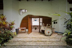 A stone staircase leading to a wooden door, a decorative cart, and a mirror on the wall.