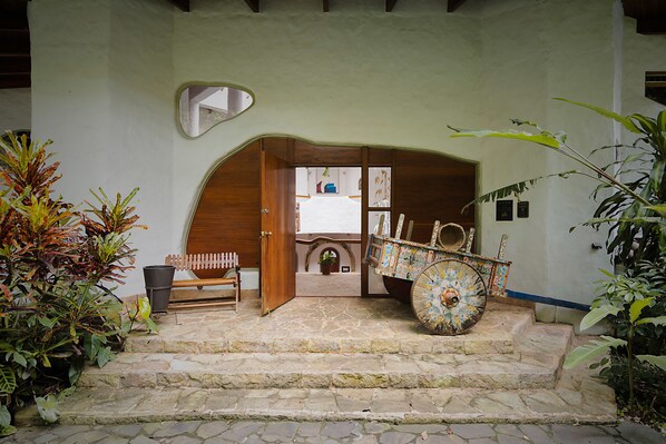 A stone staircase leading to a wooden door, a decorative cart, and a mirror on the wall.