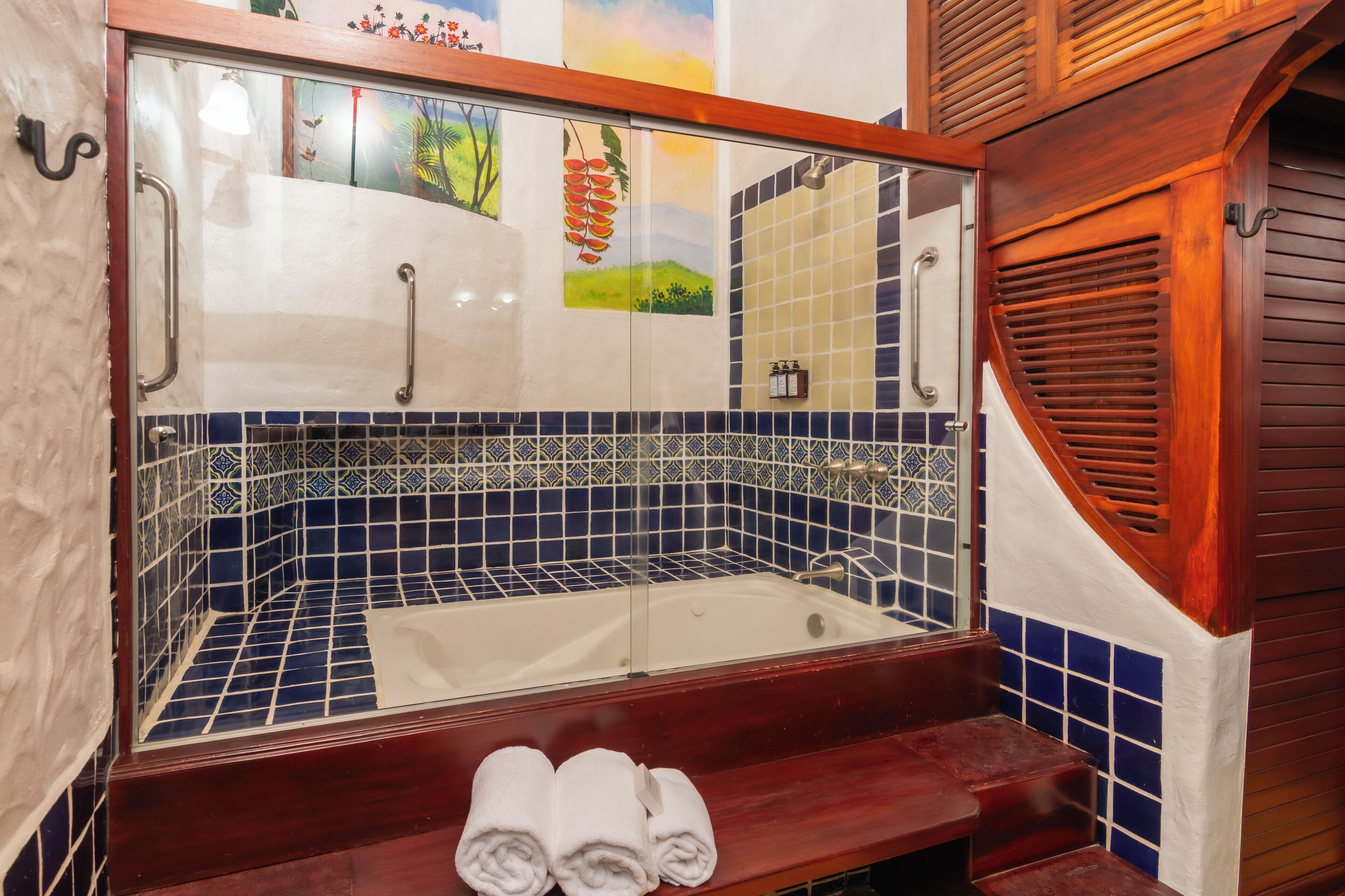 A bathroom with a bathtub, blue and white tiles, wooden steps, and a wooden door.