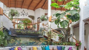 A spacious indoor area with a wooden staircase, a mural of a tropical forest, and a seating area with colorful cushions.