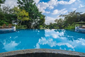 A clear blue pool surrounded by lush greenery and trees.