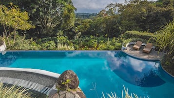 Una piscina al aire libre, sillones reclinables de piscina