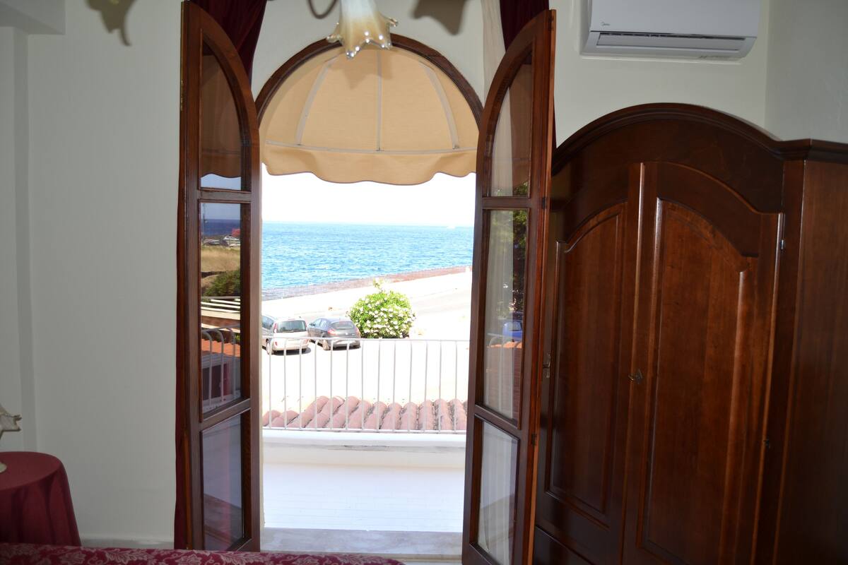 A room with a view of the sea through an open door.