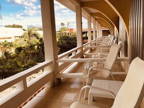 A covered outdoor seating area with white chairs and a view of the surrounding greenery and buildings. - Hotel Cabanas Maria del Mar (Isla Mujeres)