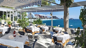 An outdoor dining area with tables and chairs, overlooking a coastal view. - Arrayanes Playa Hotel (Almunecar)