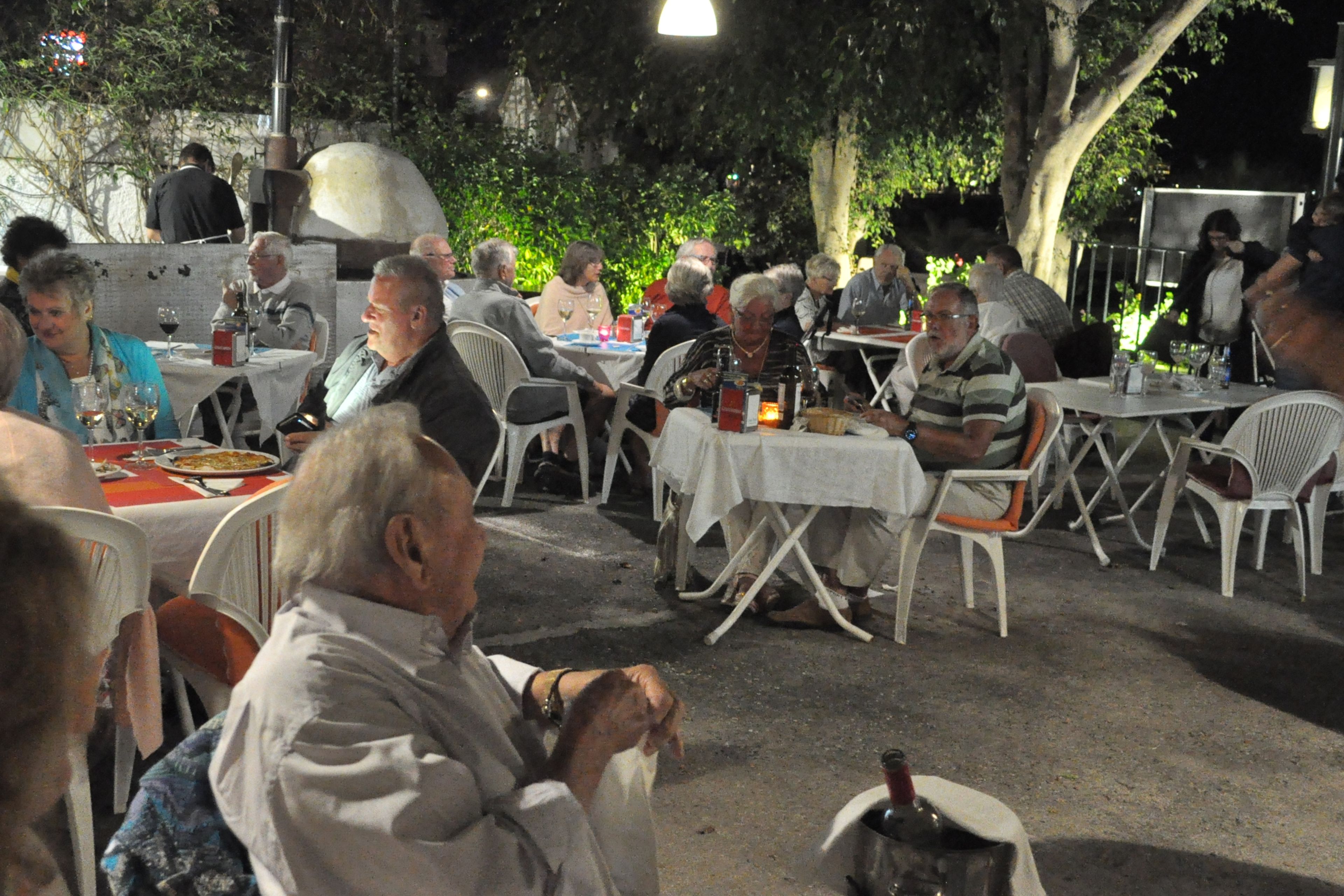 An outdoor dining area with tables and chairs, surrounded by greenery.