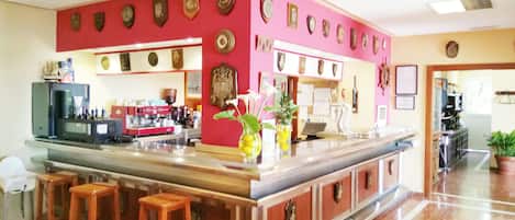Una zona de bar con mostrador, taburetes y diverso equipamiento.