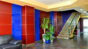 A lobby with a staircase, a leather sofa, and potted plants. - Arrayanes Playa Hotel (Almunecar)