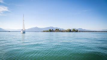A sailboat on calm turquoise waters with a distant island and mountains.