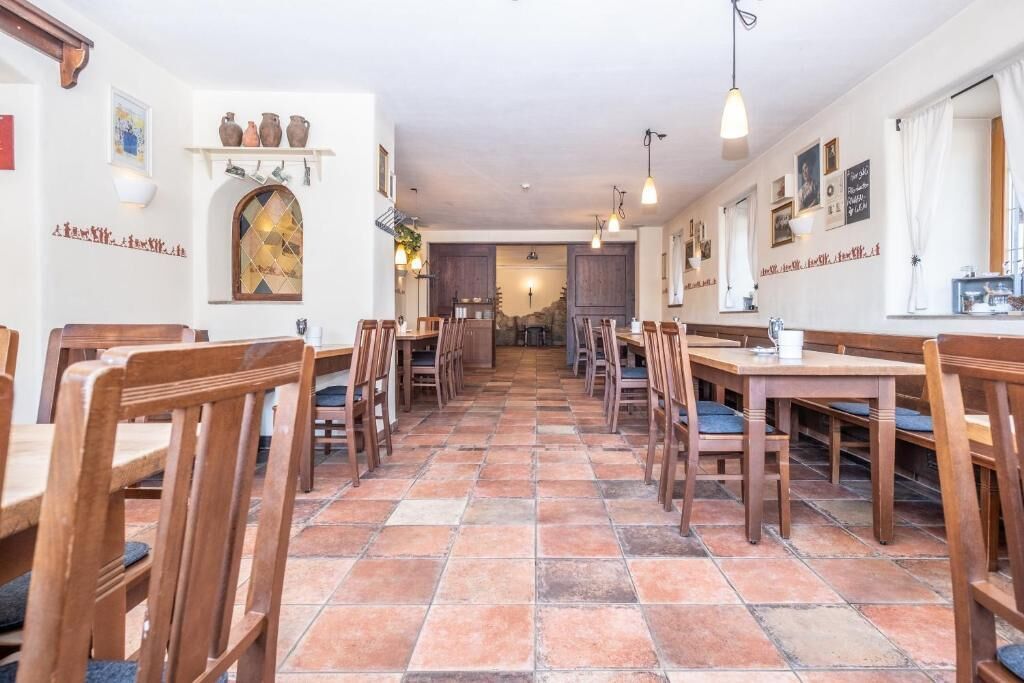 Un restaurante con mesas y sillas de madera, suelo de baldosas y luces fijadas en la pared.