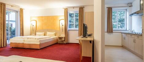 A hotel room with a bed, bedside table, TV, and a small kitchenette.