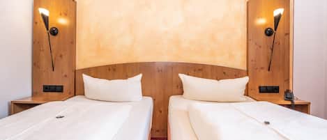 A hotel room with two single beds, wooden headboard, and bedside lamps.
