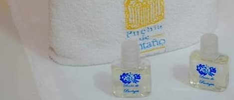 Una fila de toallas blancas dobladas con pulcritud, con logotipos bordados y dos pequeñas botellas de loción.