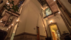 Interior amplo, com pé-direito alto, coluna central, várias varandas e iluminação embutida nas paredes.