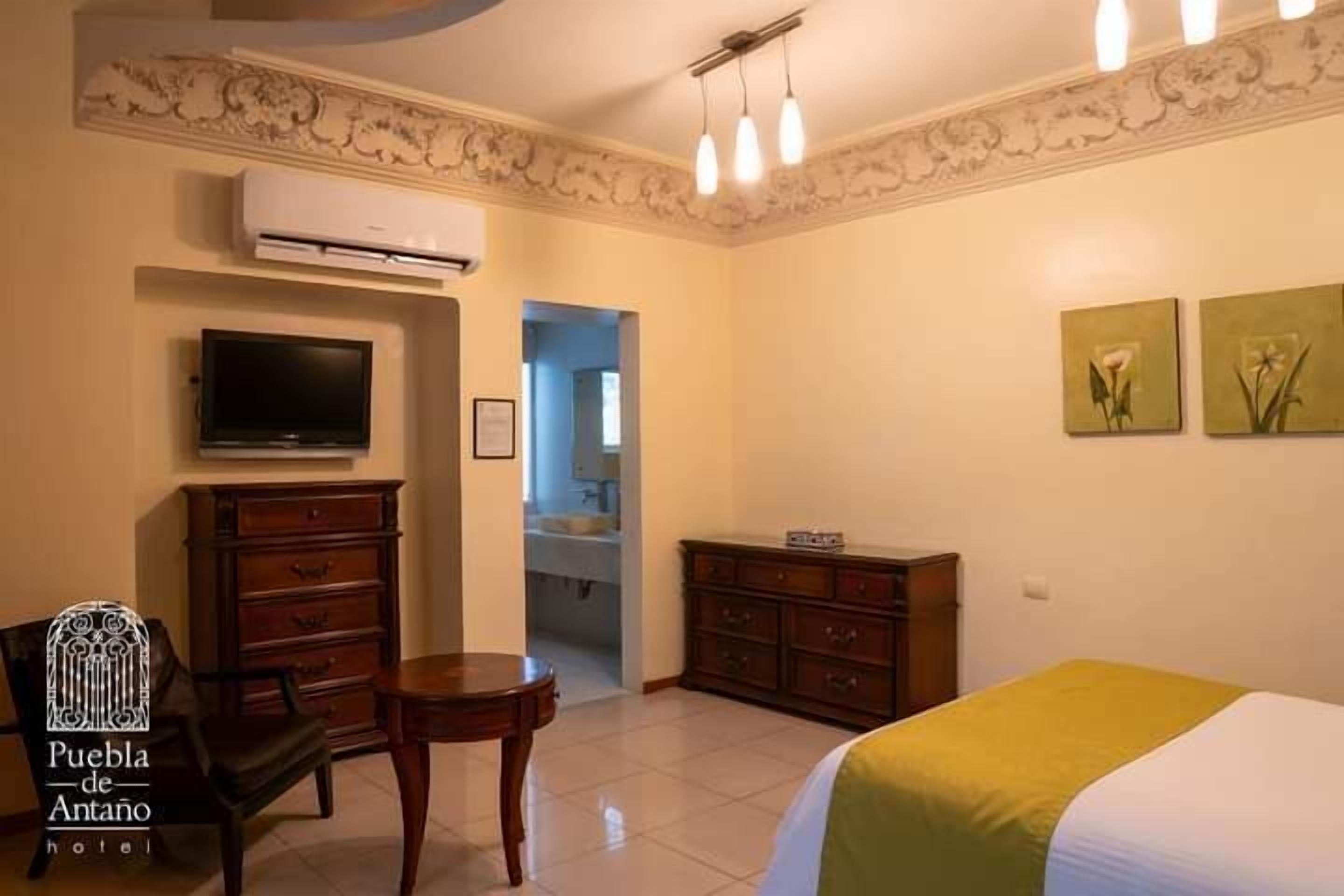 A hotel room with a bed, a television, a dresser, and a chair.