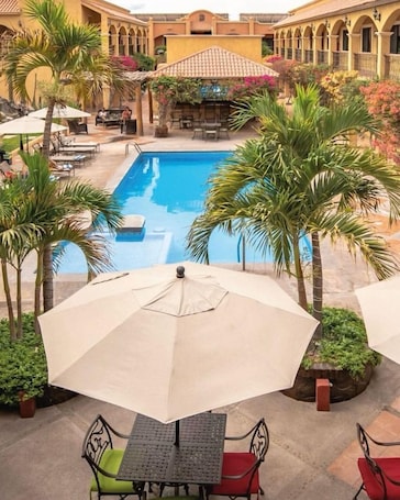 Outdoor pool, pool umbrellas, pool loungers. Hacienda Suites Loreto
