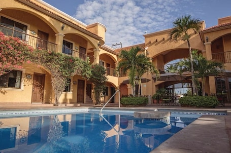 Una piscina al aire libre, sombrillas, sillones reclinables de piscina