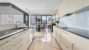 Una cocina moderna con armarios blancos, encimera negra y una zona de comedor con mesa y sillas.