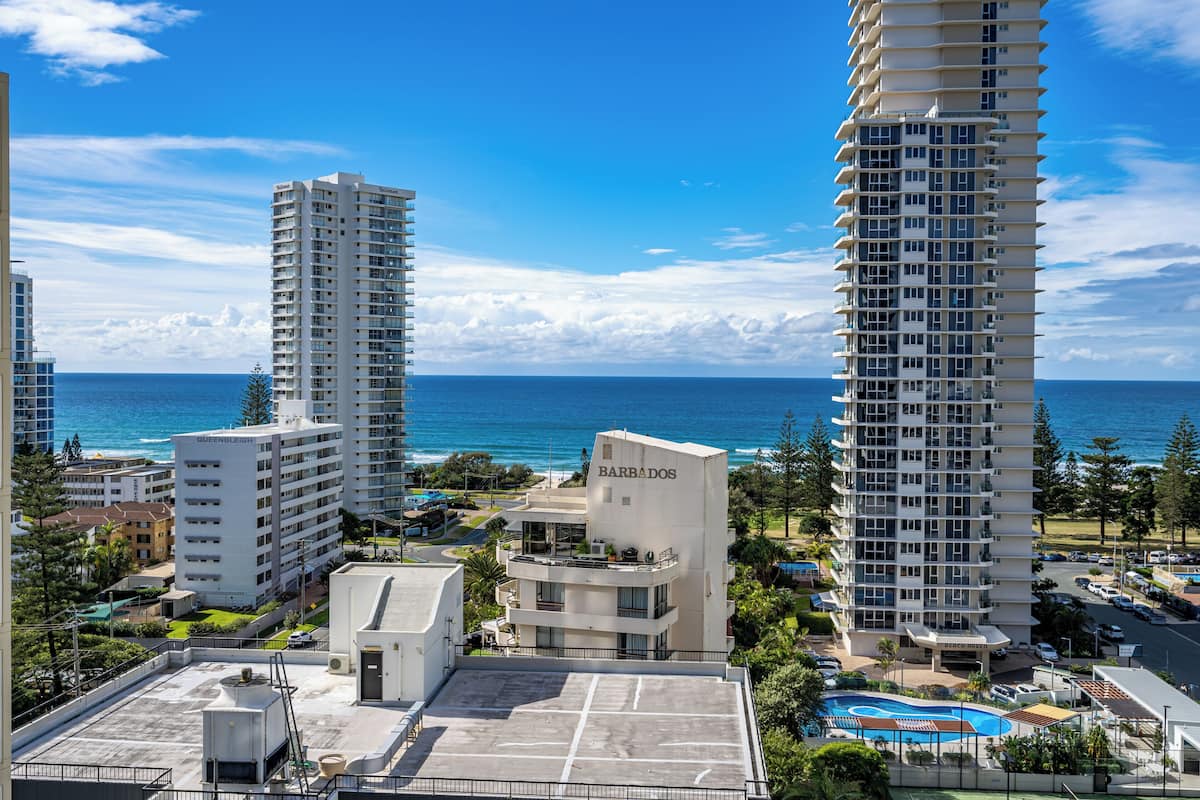 A high-rise hotel with multiple floors, a pool, and a view of the ocean.