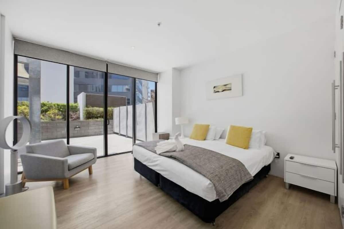 A modern bedroom with a large bed, a desk, and a chair.