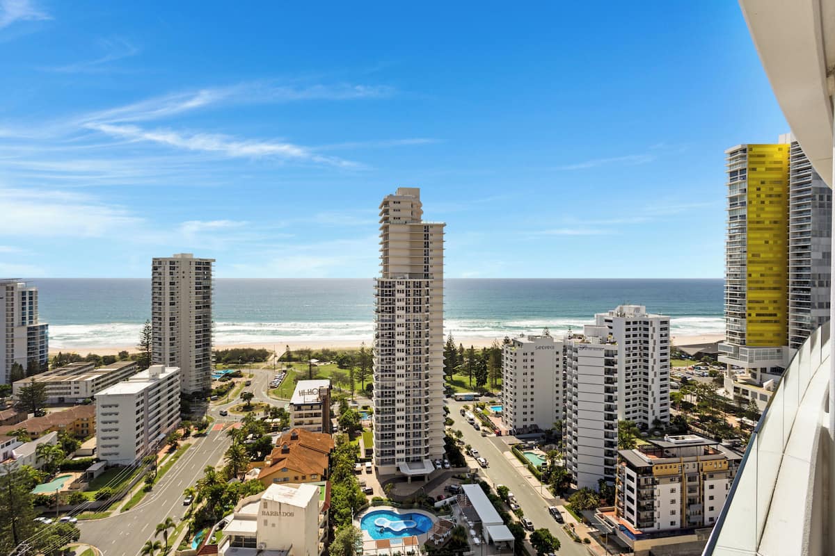 A coastal cityscape with high-rise buildings, a beach, and a swimming pool.