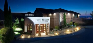 A hotel named Bryn Meadows Golf & Country Hotel with a well-lit entrance, a staircase, and a view of the surrounding landscape. - Bryn Meadows Golf, Hotel & Spa (Blackwood)