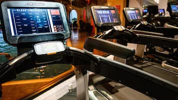 A gym with treadmills, each equipped with a digital display showing a class timetable.
