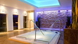 A modern indoor spa with a hot tub, stone wall, and minimalist decor. - Bryn Meadows Golf, Hotel & Spa (Blackwood)