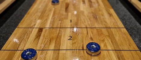 A shuffleboard table with numbered spots and blue pucks.