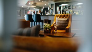 A bar area with a wooden table, a bar cart, and a bar counter. - Bryn Meadows Golf, Hotel & Spa (Blackwood)