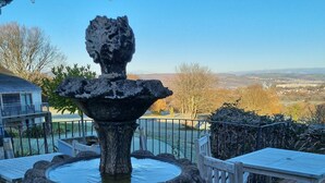 A stone fountain with a circular basin, surrounded by outdoor seating and a view of a distant landscape. - Bryn Meadows Golf, Hotel & Spa (Blackwood)
