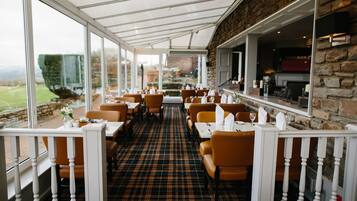A restaurant with a checkered floor, white railings, and orange chairs.