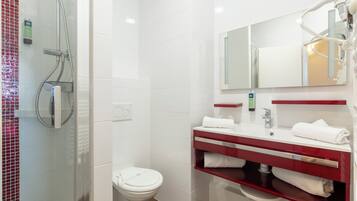 Et moderne badeværelse med en brusekabine i glas, et hvidt toilet og en vaskebordplads med rødt bord og hvid vask.