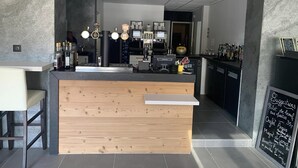 A modern bar area with a wooden counter, bar stools, and a chalkboard menu. - Logis Hôtel Arc en Ciel (Thonon-les-Bains)
