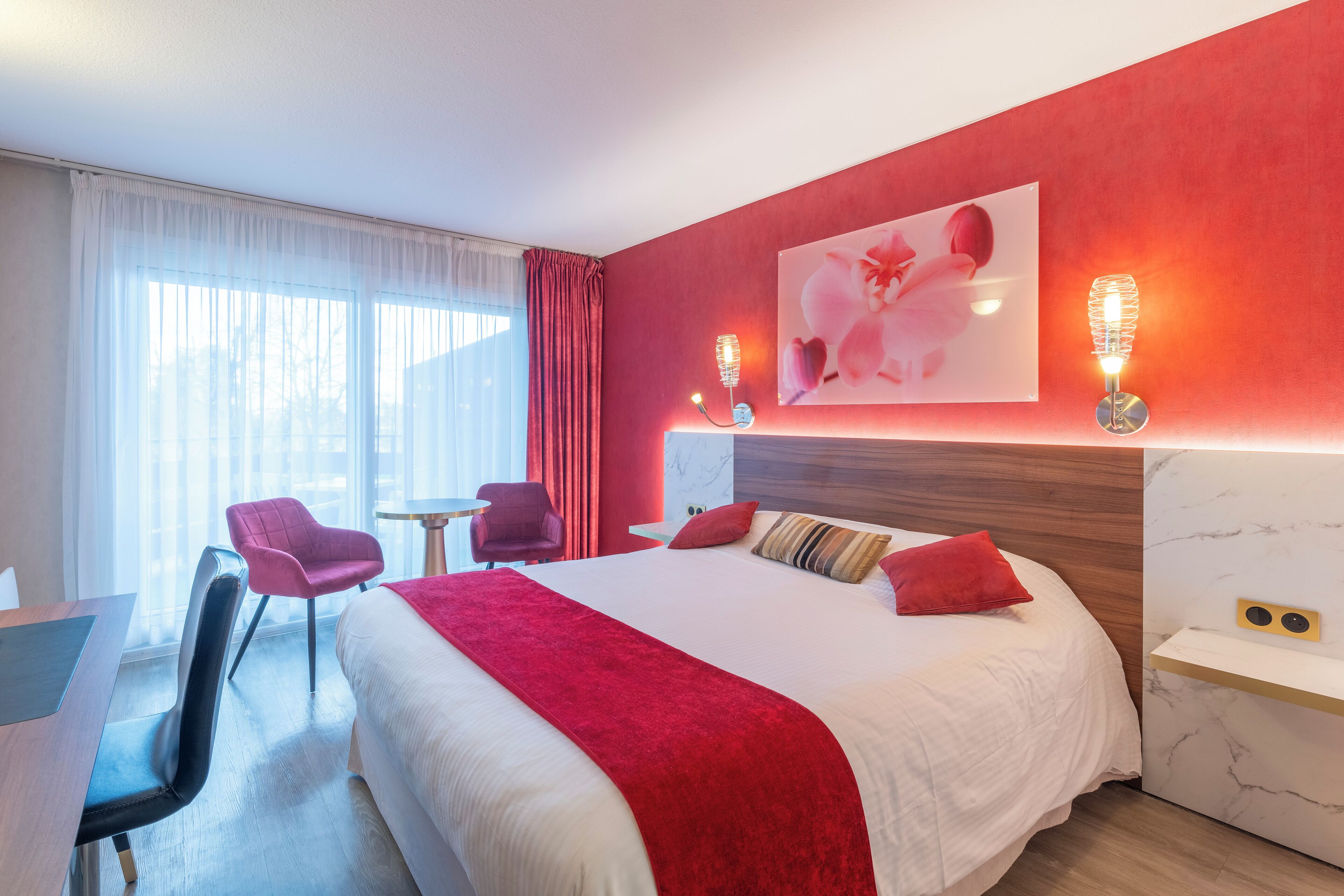 Une chambre d’hôtel avec un grand lit, un bureau, une chaise et une petite table.