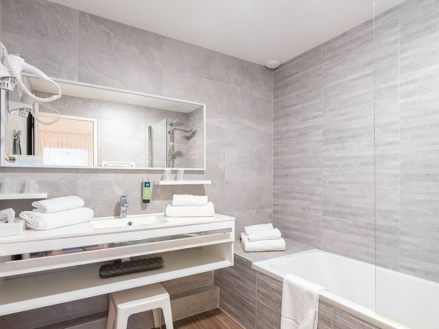 Une salle de bain moderne avec un grand miroir, un lavabo, une douche et une baignoire.