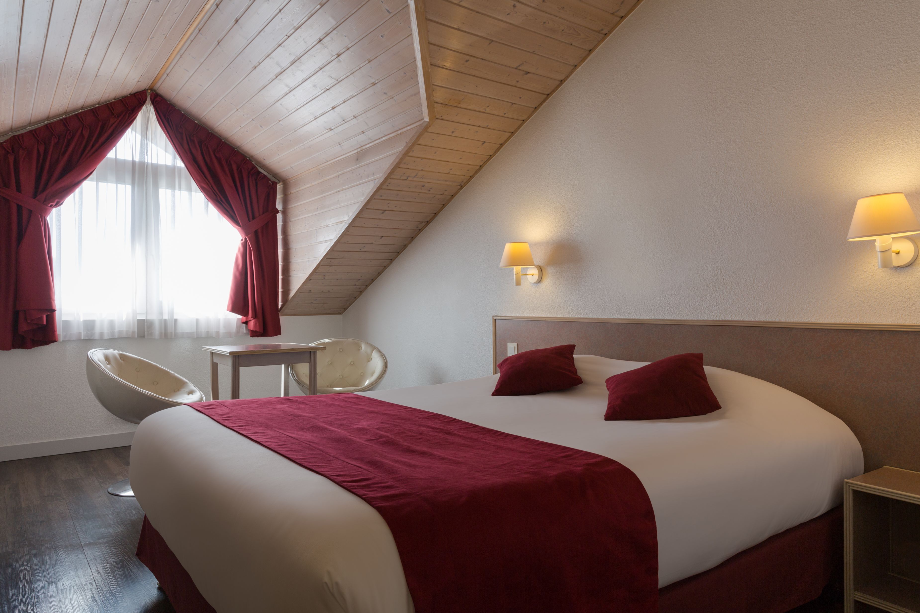 Ein Hotelzimmer mit einem großen Bett, einem Sessel, einem kleinen Tisch und einer Lampe.