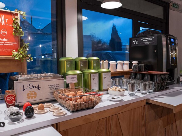Un bufé de desayuno con diversas opciones de comida, una máquina de café y vistas al exterior.