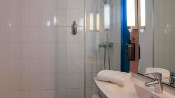 Une salle de bain moderne avec une douche à parois de verre, un lavabo blanc avec un miroir et un porte-serviettes.