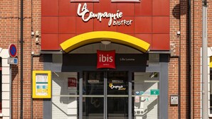 Ein Hotel Eingang mit einem rot-gelben Bogen, einem Schild für 'Compagnie Bistrot' und einem Schild von 'ibis Hotels'.
