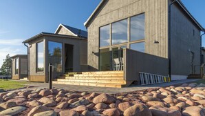 A modern wooden house with large windows, a wooden deck, and a stone pathway. - Käringsund Resort & Conference (Eckero)