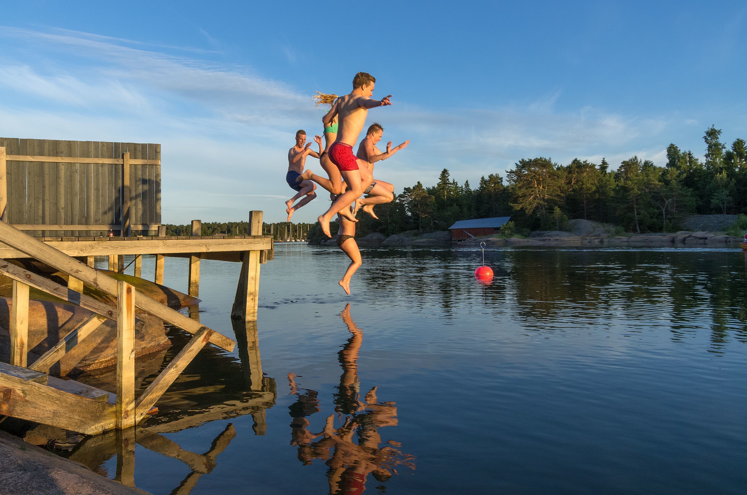 A wooden dock extending into calm water with a clear sky.