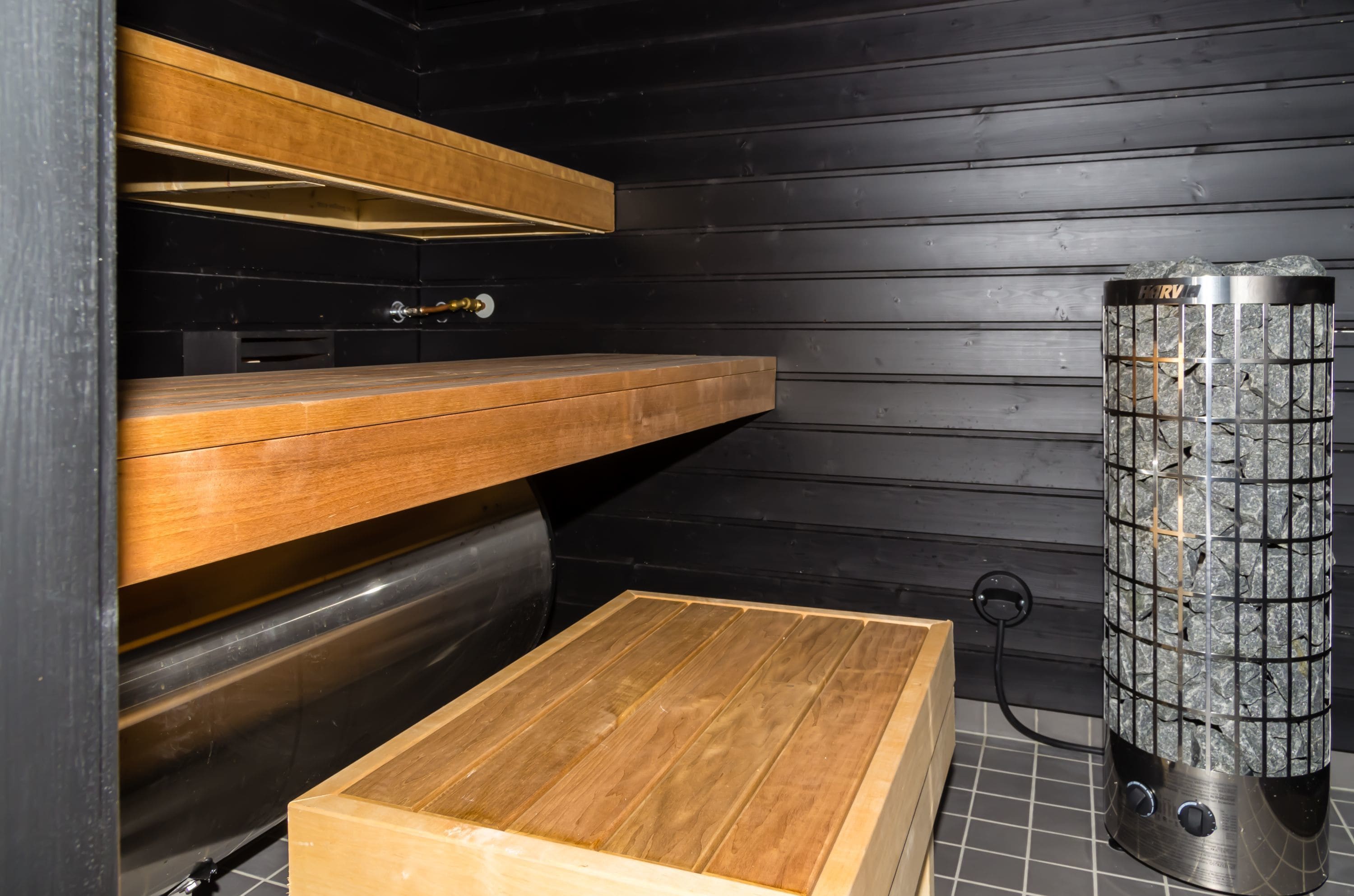 A sauna with wooden benches and a stone heater.