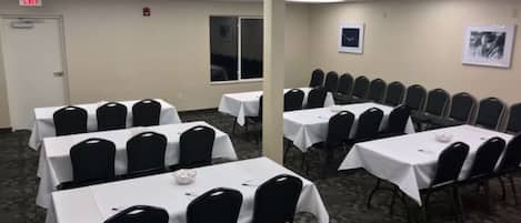 Une salle de conférence dotée de plusieurs tables et chaises, d’un revêtement de sol en moquette et d’une porte portant l’inscription « SORTIE ».