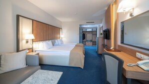 A hotel room with two beds, a desk, a chair, a TV, and a phone. - Legends Hotel Sofia (Sofia)